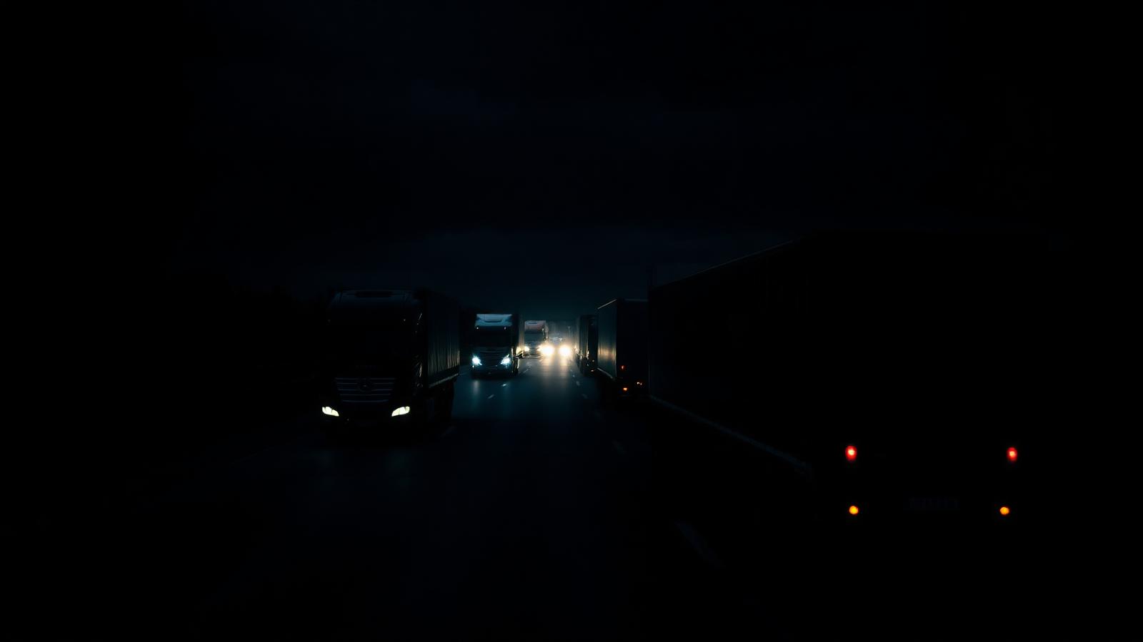 Frota de caminhões em rodovia à noite